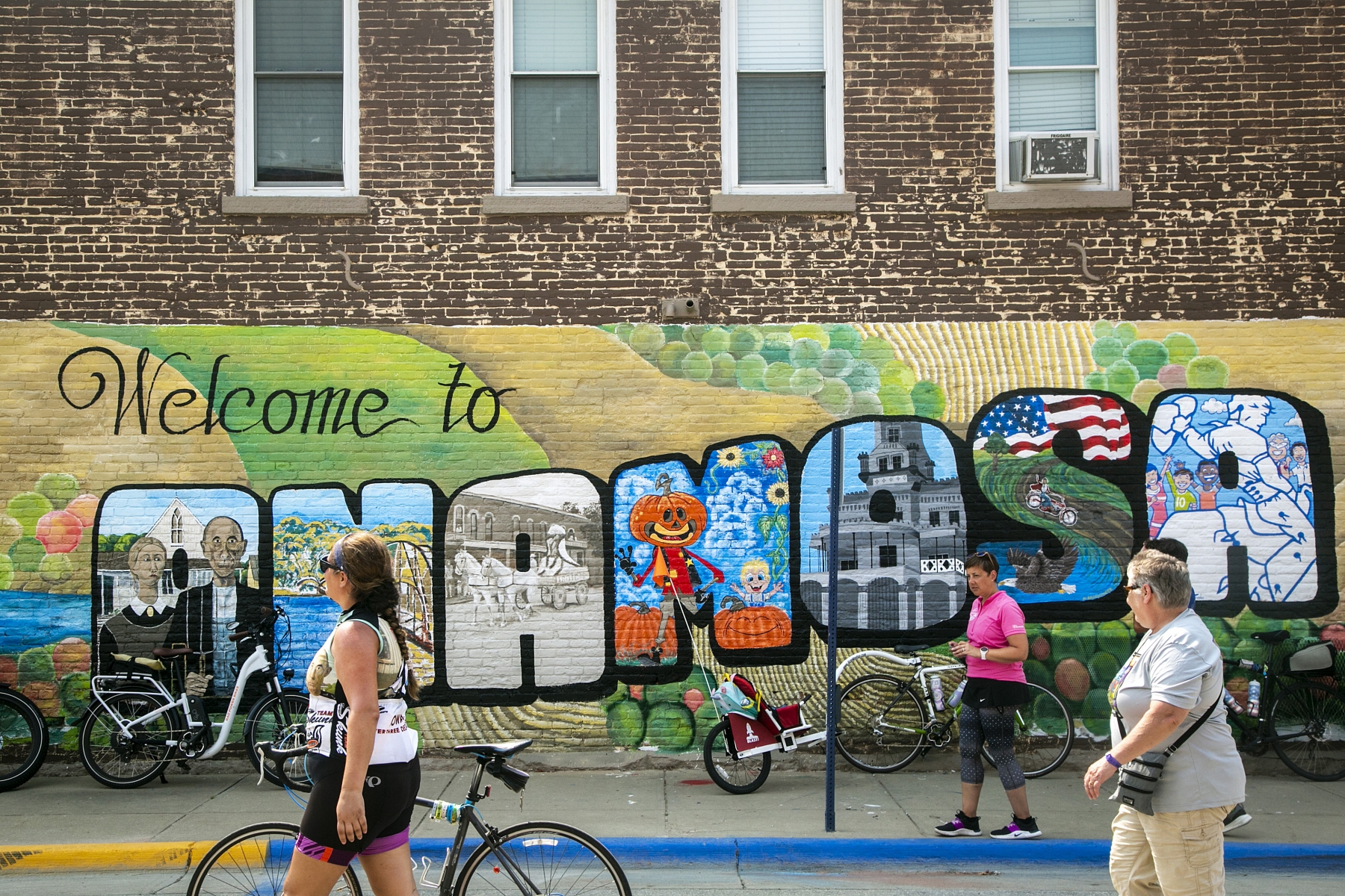 People pose for photos in front of a mural on Day 5 during RAGBRAI, Thursday, July 29, 2021, in Anamosa, Iowa.