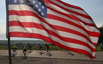 Riders make their way past the flag lined Silver City Cemetery during the first day of RAGBRAI Sunday. (Justin Hayworth/The Des Moines Register)